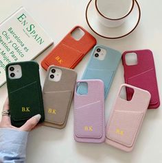 four cell phones in different colors are sitting on a table next to a cup and saucer