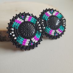 two pairs of beaded earrings sitting on top of a piece of wood