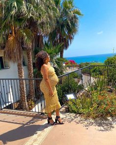 A floral chiffon print maternity midi dress featuring a smocked elastic body with ruffle trim and adjustable cami straps. Yellow Floral