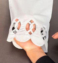 someone is holding onto some white paper with holes in it's middle and fingers