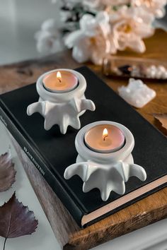 two white candles sitting on top of a book