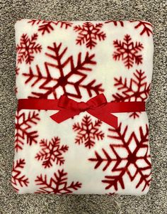 a red and white snowflake blanket with a red bow on it's side