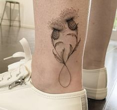 a woman's foot with a dandelion tattoo on the left side of her leg