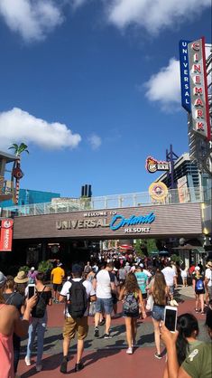 many people are walking around in front of the universal studios sign and entrance to an amusement park