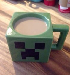 a green coffee mug sitting on top of a wooden table