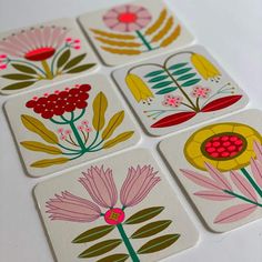 four coasters with flowers painted on them sitting on a table next to each other