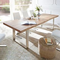 a wooden table sitting in the middle of a living room next to a white chair