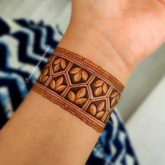 a woman's hand with a brown leather bracelet on her wrist and an intricate design