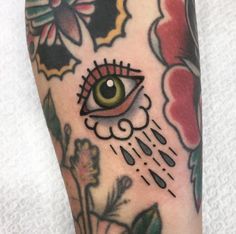 a close up of a person's leg with an eye tattoo on it and flowers