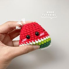 a hand holding a small crocheted watermelon