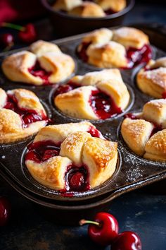 cherry pastries in a muffin tin with fresh cherries on the side, ready to be eaten