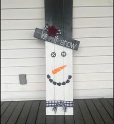 a snowman made out of wooden planks with a sign that says let it snow