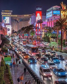 a busy city street filled with lots of traffic next to tall buildings and palm trees