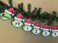 a christmas garland with green and red ornaments hanging from it's sides on a wall