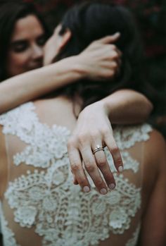 two women are hugging each other and one is wearing a wedding ring on her finger