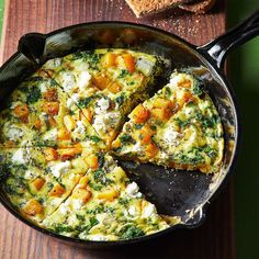 an omelet with spinach and cheese in a skillet on a wooden table