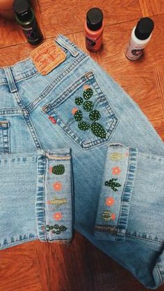 the jeans have cactus patches on them and are sitting on the floor next to other items