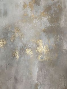 an abstract painting with gold and silver paint on the wall, in shades of gray and yellow