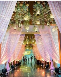 the inside of a building decorated with white drapes and lights