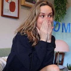 a woman covers her mouth while sitting on a couch