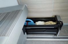 an open drawer in the back of a car seat next to a mattress and pillow