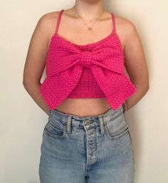 a woman wearing a pink top with a big bow on it's back and her hands in her pockets