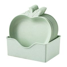 an apple shaped dish is stacked in a white container with four forks and two spoons