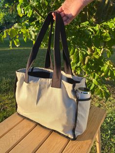 Beige and Black Canvas Tote Bag has a beige body, black piping, water-resistant, lightweight, foldable, sustainable, canvas with different color combinations, and is lined and suitable for organization with pockets. It has two side pockets, one inside and one outside. It is handmade. Books, Ipads, Macbooks, etc. It is perfect for. Suitable for use in all seasons and conditions, your bag will age beautifully over time with its quality and durability. Never use bleach, solvents, etc. Do not use ch Rectangular Canvas Bag With Zipper Pocket For Outdoor Activities, Outdoor Canvas Tote Bag With Removable Pouch, Beige Rectangular Canvas Bag For Outdoor, Eco-friendly Reversible Canvas Travel Bag, Reversible Eco-friendly Canvas Travel Bag, Black Canvas Tote Bag, Waterproof Tote, Body Black, Small Tote Bag