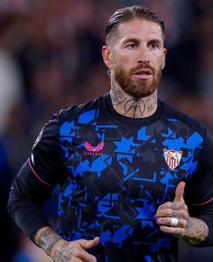 a man with tattoos on his arms and chest standing in front of a soccer field