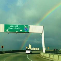 a rainbow is in the sky over a highway