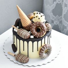 there is a cake that has ice cream and donuts on it, with chocolate drizzles