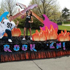 two people are posing in front of a rock and roll sign with guitars on it