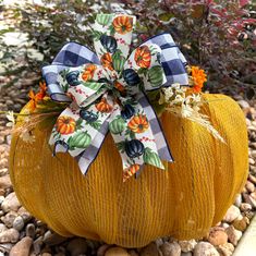 a pumpkin with a bow sitting on some rocks