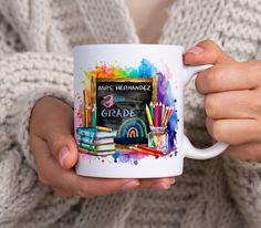 a person holding a coffee mug with school supplies painted on the front and back side