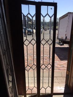 an open glass door on the side of a building with a truck in the background