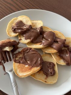 chocolate spread on crepes sitting on top of a white plate with a fork