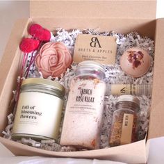 an open box containing bath salts, candles and soaps with flowers on the side