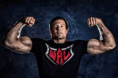 a man flexing his muscles in front of a dark background