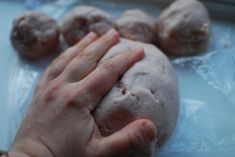 a person's hand on top of some doughnuts