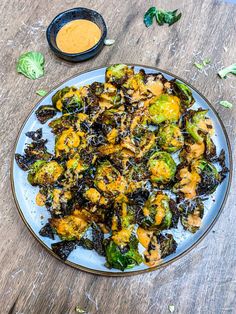 broccoli and cauliflower on a plate with dipping sauce next to it