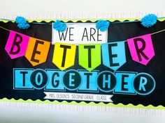 we are better together banner with blue pom poms hanging from it's sides