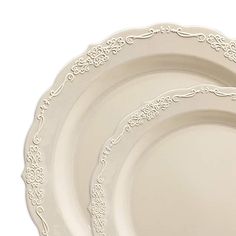 three white dinner plates with ornate designs on the rims, set against a white background