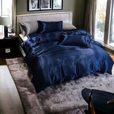 a bed with blue comforter and pillows in a bedroom next to two pictures on the wall