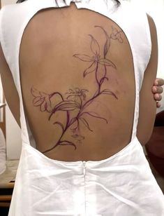 the back of a woman's white dress with purple flowers on her lower back