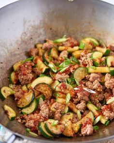 a pan filled with meat and zucchini on top of a table next to a knife