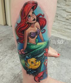 the little mermaid tattoo on the leg is very colorful and has an image of her favorite character