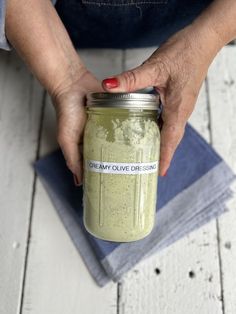 a person holding a mason jar filled with green smoothie