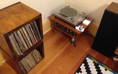 a record player sitting on top of a wooden floor next to a shelf filled with records