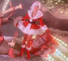 two women dressed as santa clause and mrs claus in front of a christmas tree with lights