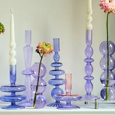 there are many different colored vases on the table with one flower in it and two candles next to them